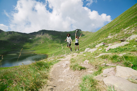 Young couple jumping in a big valley with a lake