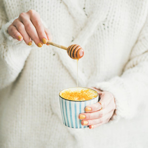 Healthy turmeric latte or golden milk with honey  square crop