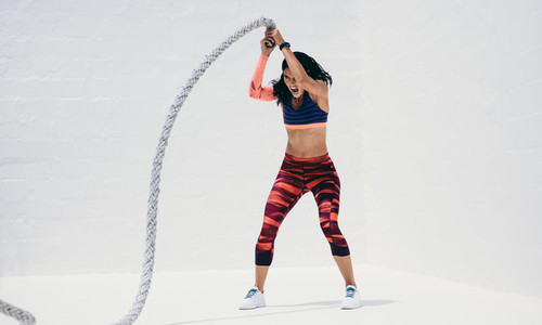 Fitness woman working hard on a battle rope