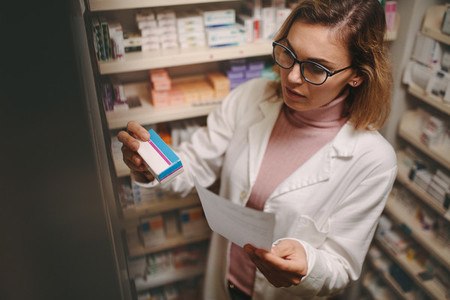 Female pharmacist with prescription checking medicine