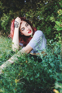 Young and beautiful redhead woman posing surrounded by nature