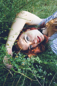Young and beautiful redhead woman posing surrounded by nature