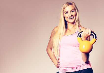 Woman wearing workout clothes holding a kettlebell