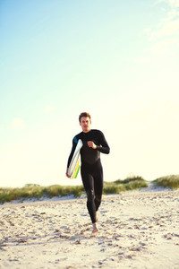 Energetic surfer running across the beach