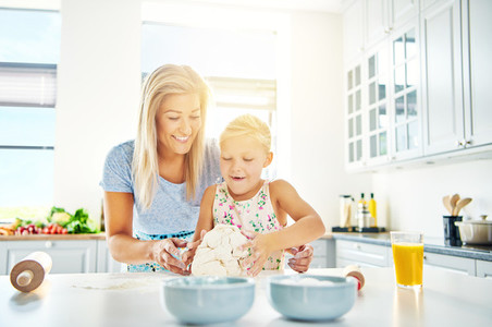 Happy child learning to bake with her mother