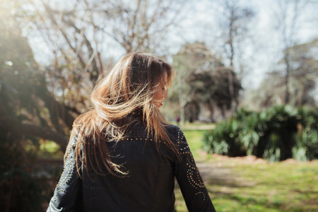 Young blonde woman from behind moving her hair in the park