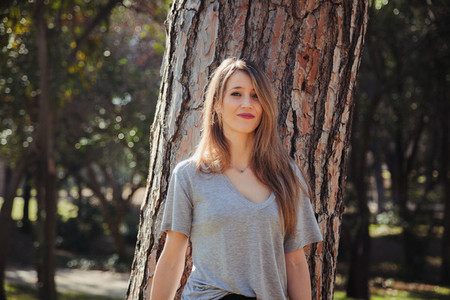 Young smiling blonde woman wearing a grey t shirt in the park