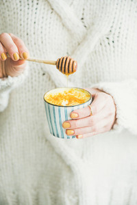 Turmeric latte  golden milk with honey in womans hands