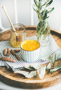Turmeric latte or golden milk with honey in cup