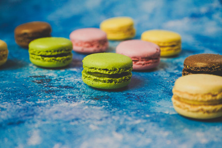 Variety of colorful macarons over a blue background