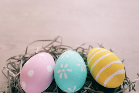 Pastel and colorful easter eggs on nest with wooden background a