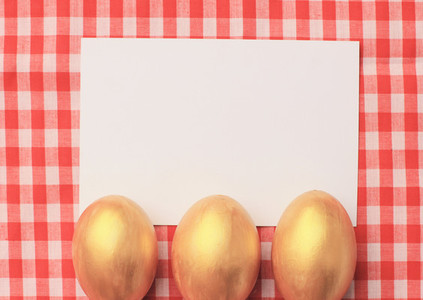 Golden easter eggs on red checkered tablecloth background with b