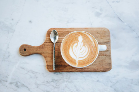 Top view of hot latte coffee on wooden tray on marble table back