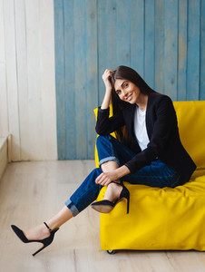Young woman sitting on yellow sofa