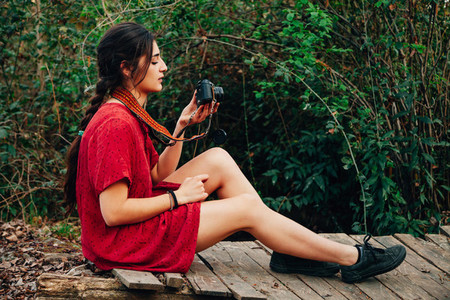 Young woman taking photos in the forest wearing a mini dress