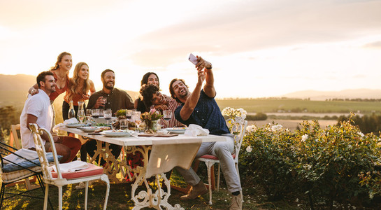 Group of friends taking selfie at dinner party