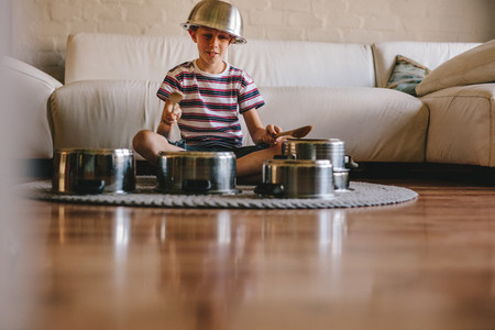 Little musician playing drums on kitchenware