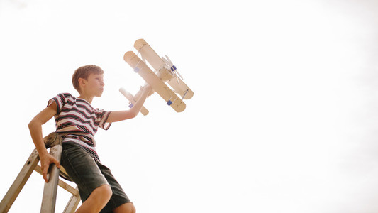Boy on top of a ladder with toy airplane