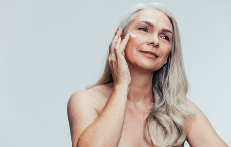 Senior woman putting on anti aging cream