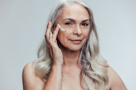Senior woman applying anti aging face cream