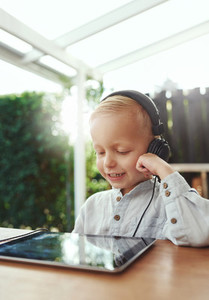 Little boy smiling in delight listening to music