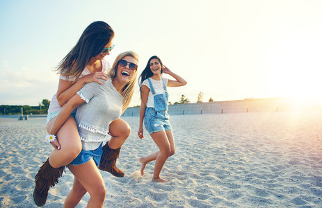 Three happy girlfriends running on the beach
