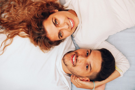 Young smiling heterosexual couple lying down together on the bed