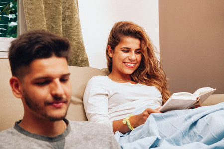Young smiling heterosexual couple together on sofa