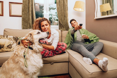 Young smiling couple together on sofa whit their dog