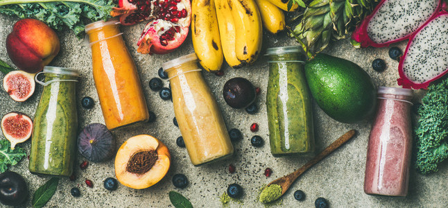 Colorful smoothies in bottles with fresh fruit copy space