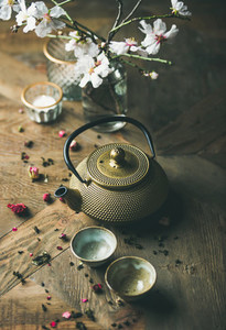 Golden iron teapot  cups  dried rose  candles and almond flowers