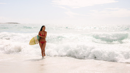Woman with surf board walking out of the sea