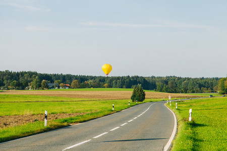 Yellow hot air balloon taking off near a county road in Germany