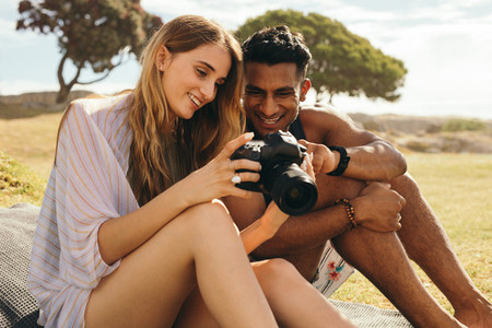 Tourist couple sitting outdoors holding a dslr camera