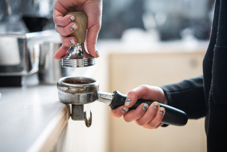 Barista presses ground coffee using tamper
