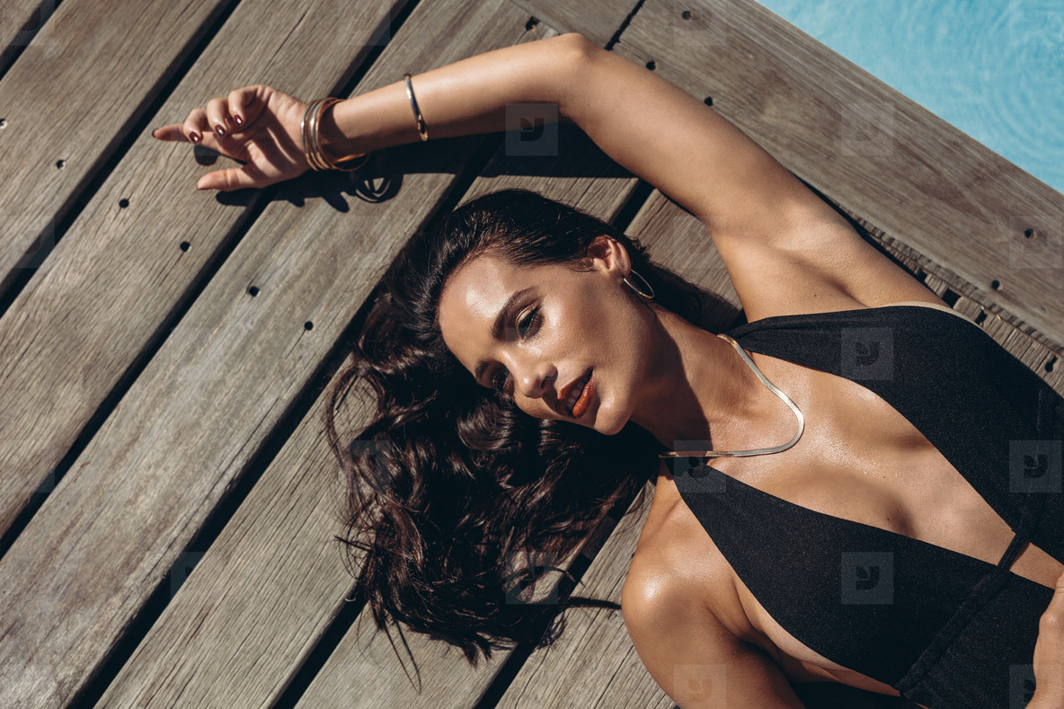 Sensual woman sunbathing at poolside