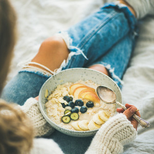Woman in jeans and sweater eating vegan breakfast  square crop