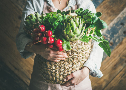 Female farmer holding basket of fresh garden vegetables  horizontal composition