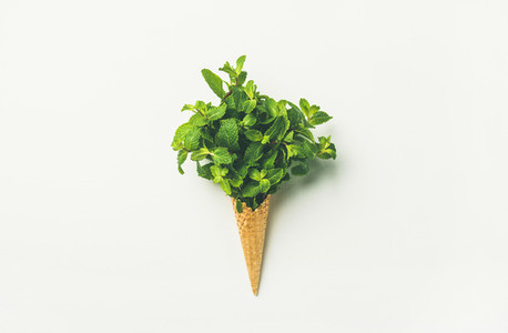 Waffle cone with fresh mint leaves over white background  flat lay