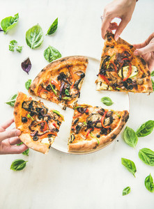 Peoples hands taking Freshly baked vegetarian pizza over marble background