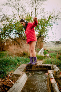 Girl with headphones and raincoat washing her waterproof boots
