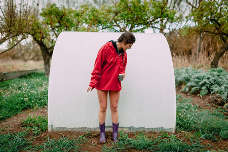 Girl with raincoat in her orchard while it is raining