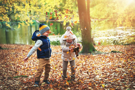 Two children playing with leaves in forest