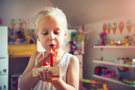 Cute girl blowing to red toy candle