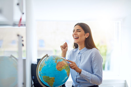 Laughing woman pointing to country on globe