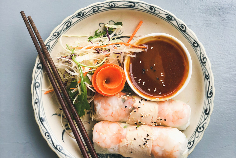 Asian style dinner. Flat-lay of steamed dumplings Dim sum and summer rice paper rolls with shrimp and sauce over blue table, top view, copy space. Chinese cuisine
