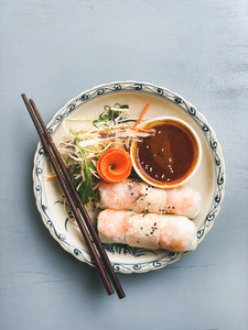 Asian style dinner  Flat lay of steamed dumplings Dim sum and summer rice paper rolls with shrimp and sauce over blue table  top view  copy space  Chinese cuisine