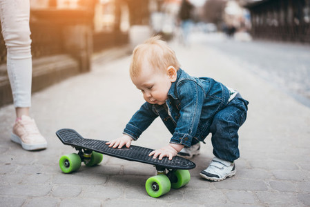 little funny boy with skateboard on the street