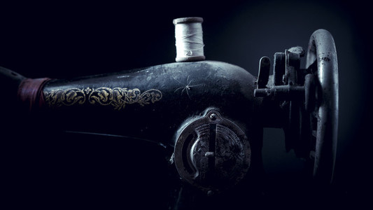 Old abandoned sewing machine on a black background