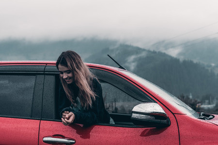 cute girl leaning out of an open car window enjoy background mountains